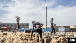 Des enfants ramassent des briques de maisons démolies pour construire un abri à Xwlacodji, dans le 5ème arrondissement de Cotonou, le 3 septembre 2019, après le passage des bulldozers.