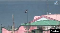 FILE - A still image taken from a video posted to a social media website by the Islamic State-affiliated Amaq News Agency on June 12, 2017, shows a black flag perched on a building in Marawi City, Philippines.