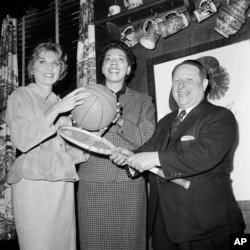 Tennis stars Althea Gibson, center, and Karol Fagerol are shown with Harlem Globetrotters' owner Abe Saperstein, where the women signed a professional contract with the Globetrotters to play at exhibition matches, Oct. 19, 1959 in New York.