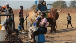 A woman smiles while playing with her baby at a water point on the outskirts of the capital Harare, Nov, 14, 2021.