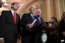 Senate Majority Leader Mitch McConnell, R-Ky., flanked by Sen. John Barrasso, R-Wyo., left, and Majority Whip John Cornyn, R-Texas, speaks to reporters about efforts to avoid a government shutdown this weekend, at the Capitol in Washington, Jan. 17, 2018.