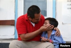 미국 정부의 '무관용 이민정책'에 따라 격리됐던 불법 이민자 부모와 미성년자 아들이 한 달여만에 상봉한 후 서로에게 기대어 앉아있다.