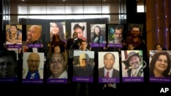 San Bernardino County employees hold up photos of the San Bernardino shooting victims during a candlelight vigil on Dec. 7, 2015, in San Bernardino, Calif.