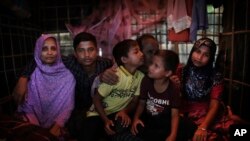In this Nov. 25, 2017, photo, Bodru Duza, 52, third from right, kisses his sons as he sits for a portrait with members of his family in a tent in Kutupalong refugee camp in Bangladesh.