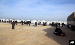 In this photo provided by Turkey's Islamic aid group of IHH, Syrians fleeing conflict in their country's Azaz region, are seen at a temporary accommodation center set up by the group near the Bab al-Salam border crossing, Syria, Feb. 5, 2016.