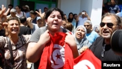 Assassinated Tunisian opposition politician Mohamed Brahmi's daughter Balkis (C) holds a Tunisian flag as she mourns his death in Tunis, July 25, 2013.