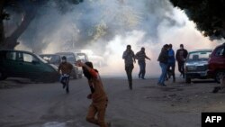 Anti-government protesters run for cover during clashes with police in Helwan on the outskirts of Cairo on December 27, 2013.