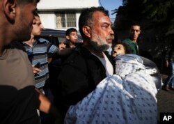 Akram Mogdadm holds the body of his son, Baraa, 6, who was killed along with 9 other people, all but one of them children, in an explosion at a park at Shati refugee camp, in the northern Gaza Strip, July 28, 2014.