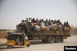 Migrants sit on their belongings in the back of a truck as it is driven through a dusty road in the desert town of Agadez, Niger, headed for Libya, May 25, 2015.
