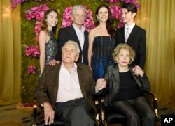 Actor Kirk Douglas (seated left) holds hands with his wife Anne Douglas as they pose with family members, their son Michael (standing second left), his wife Catherine Zeta-Jones (standing second right), and their children, Carys Zeta Jones (left) and son Dylan during Kirk's 100th birthday party at the Beverly Hills Hotel, Dec. 9. 2016, in Beverly Hills, Calif.