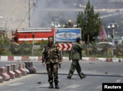 An Afghan security personnel holds his gun as he keeps watch near the site of a car bomb blast at the entrance gate to the Kabul airport in Afghanistan, August 10, 2015.