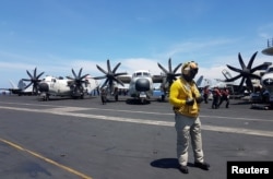 An air traffic controller guides aircraft landing on the deck of the USS Theodore Roosevelt, transiting the South China Sea April 10, 2018.