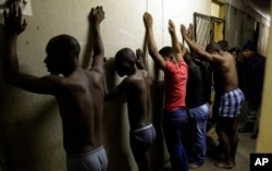 Men stand against a wall as police officers search their room during a raid at an Alexandra township hostel considered a hot spot for anti-immigrant attacks in Johannesburg, South Africa, April 23, 2015.