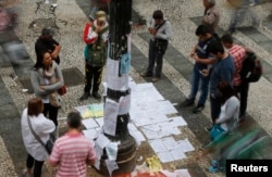 People look at a list of job offers posted in a main street in downtown Sao Paulo, Aug. 13, 2014.