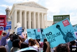 FILE - Protesters hold up signs and call out against the Supreme Court ruling upholding President Donald Trump's travel ban outside the the Supreme Court in Washington, June 26, 2018.