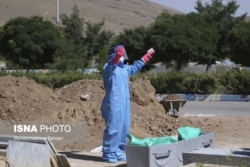 Iran --A cemetery worker preforms an Islamic prayer over the body of a COVID-19 victim.