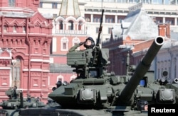 A Russian serviceman aboard a tank salutes during the Victory Day parade in Moscow's Red Square, May 9, 2014.
