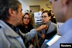 Hossein Khoshbakhty, left, speaks with attorney Talia Inlender about his Iranian family members effected by the travel ban as Homa Homaei, second from left, looks on outside the U.S. Customs and Border Protection office at Los Angeles International Airpor