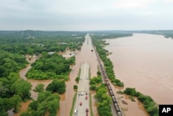 The Arkansas River spills over, flooding a highway in Sand Spring, Okla., May 28, 2019.