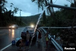A family bathe and wash their car with mountain spring water in Utuado, Puerto Rico, Nov. 9, 2017, as the territory continues to deal with the aftermath of Hurricane Maria, which struck in September.