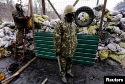 Ukrainian anti-government protesters stand near a passage in a barricade at the site of recent clashes with riot police in Kyiv, Feb. 17, 2014.