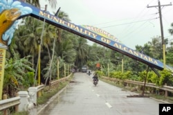FILE - Motorists drive past a fallen marker that was toppled by Tropical Storm Jangmi at Alcantara township, Cebu province, central Philippines, Dec. 30, 2014.