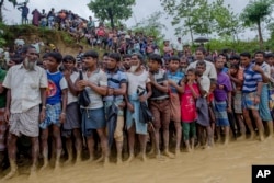 Rohingya Muslim men and boys, who crossed over from Myanmar into Bangladesh, wait for their turn to collect food items distributed by aid agencies in Balukhali refugee camp, Bangladesh, Sept. 19, 2017.