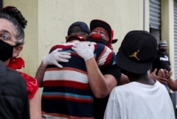 Flavio Falcone hugs a man as Andrea Macera, talks to other men as they check on people in an area known as "cracolandia" in the historic center of Sao Paulo, Brazil, February 9, 2021. REUTERS/Amanda Perobelli