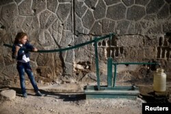 FILE - A girl fills a container with water in the Douma neighborhood of Damascus, Sept. 12, 2016.