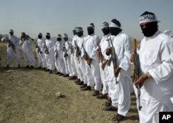 File -Taliban suicide bombers stand guard during a gathering of a breakaway Taliban faction, in the border area of Zabul province, Afghanistan, Aug. 15, 2016.