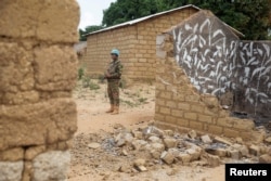 FILE - A United Nations peacekeeper stands among houses destroyed by violence in the abandoned village of Yade, Central African Republic, April 27, 2017.