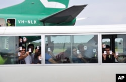 FILE - A group of asylum seekers hold up their identity cards after landing in Manus Island, Papua New Guinea. The United States has agreed to resettle an unspecified number of refugees languishing in Pacific island camps.