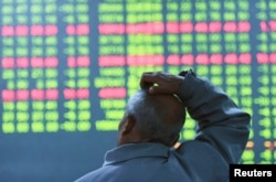 FILE - An investor looks at an electronic screen showing stock information at brokerage house in Hangzhou, Zhejiang Province, China, Jan. 11, 2016.
