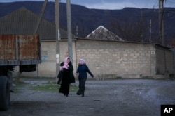 FILE - local residents walk in a street in the village of Komsomolskoye, Dagestan, Russia, Nov. 12, 2015.