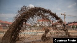 March 27, 2009 - Phnom Penh, Cambodia. A child plays in muddy water that is spraying out of a broken pipe, the pipes are pumping sand into a natural lake in Borei Reakreay community. The community was evicted from their homes in mid-2009 to make way for r