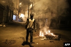 An armed Kurdish militant walks in the Okmeydani district of Istanbul during a demonstration against recent curfews imposed on Kurdish towns, Dec. 15, 2015.