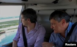 Argentina's Cabinet Chief Marcos Pena, left, and Chaco province Governor Domingo Peppoi fly on a helicopter over flooded areas near Resistencia, Argentina, Dec. 26, 2015.