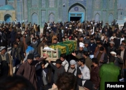 FILE - Afghan men attend a funeral ceremony of an International Committee of the Red Cross (ICRC) employee, who was killed by gunmen in Mazar-i-Sharif, Afghanistan, Feb. 9, 2017.