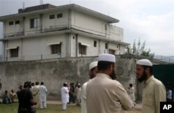 FILE - In this May 5, 2011 file photo, local residents and media are seen outside the house where al-Qaida leader Osama bin Laden was caught and killed in Abbottabad, Pakistan.