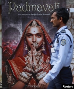 A security guard walks past a poster of the upcoming Bollywood movie "Padmavati" outside a theater in Mumbai, India, Nov. 21, 2017.