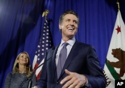 Democratic Lt. Gov. Gavin Newsom, right, speaks at his gubernatorial campaign's primary night watch party next to his wife Jennifer Siebel Newsom in San Francisco, June 5, 2018.