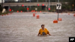 A woman who identified herself as Valerie walks along flooded President Street after leaving her homeless camp after Hurricane Matthew caused flooding, Oct. 8, 2016, in Savannah, Ga.