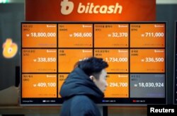 FILE - A man walks past an electric board showing exchange rates of various cryptocurrencies, including Bitcoin, at a cryptocurrencies exchange in Seoul, South Korea, Dec. 13, 2017.