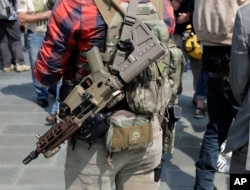 A man standing with members of Patriot Prayer and other groups supporting gun rights carries guns during a rally, Aug. 18, 2018, at City Hall in Seattle.