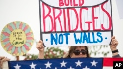 Lauren Rees holds up a sign during a rally against a scheduled visit by President Donald Trump, March 13, 2018, in San Diego. Protesters chanted, “No ban! No wall!” near the San Ysidro border crossing, where tens of thousands of people enter the U.S. daily from Tijuana, Mexico, many on their way to work or school in San Diego.