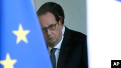 French President Francois Hollande is seen through the glass door after a security meeting at the Elysee palace in Paris, Nov. 14, 2015.