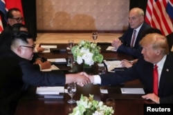 U.S. President Donald Trump and North Korea's leader Kim Jong Un shake hands during an expanded bilateral meeting at the Capella Hotel on the resort island of Sentosa, Singapore, June 12, 2018.