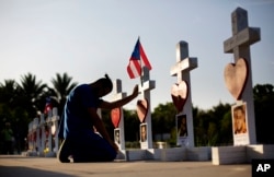 FILE - Ernesto Vergne prays at a cross honoring his friend Xavier Emmanuel Serrano Rosado and the other victims at a memorial to those killed in the Pulse nightclub mass shooting a few blocks from the club in Orlando, Florida, June 17, 2016.