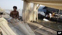 FILE - A Cambodian man fixes his fishing nets during the dry season on the Mekong river bank, Feb. 28, 2012