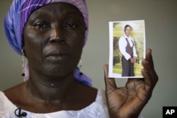 FILE - Martha Mark, the mother of kidnapped school girl Monica Mark cries as she displays her photo, in the family house, in Chibok, Nigeria.